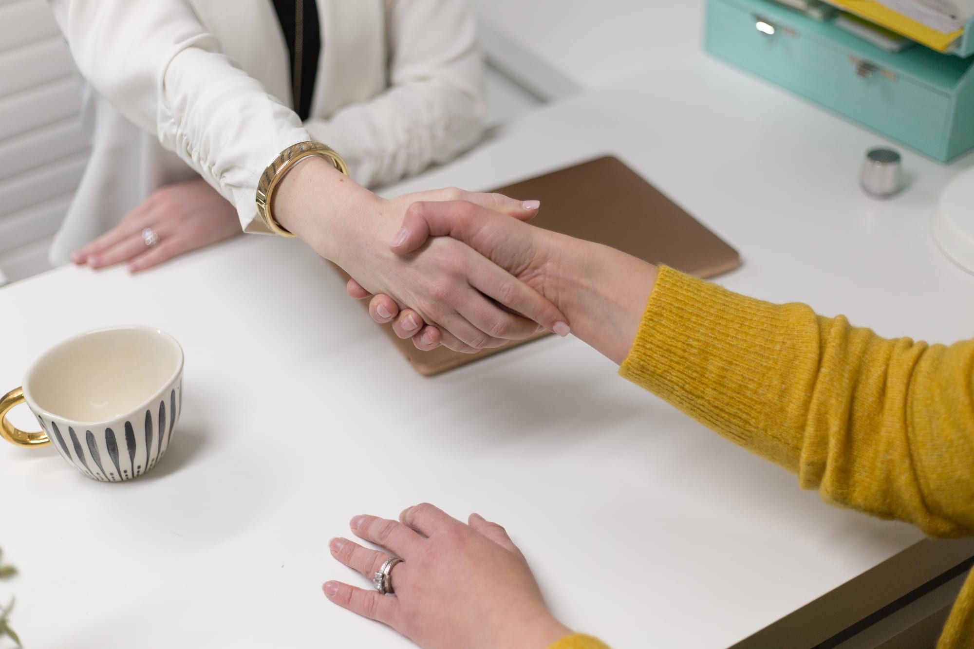 An agent and a client shaking hands across a desk