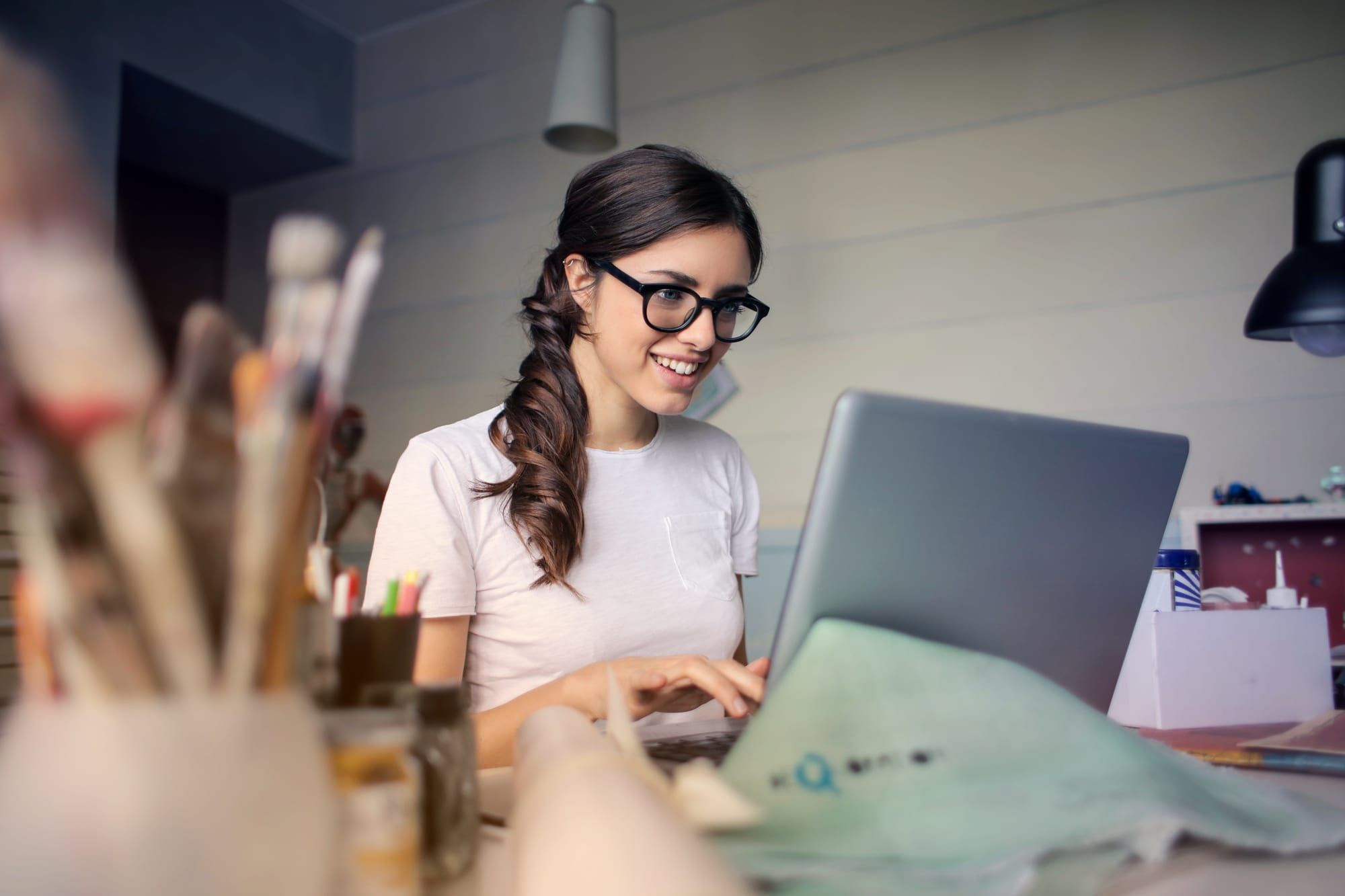 An assistant smiling while working on a laptop at her desk