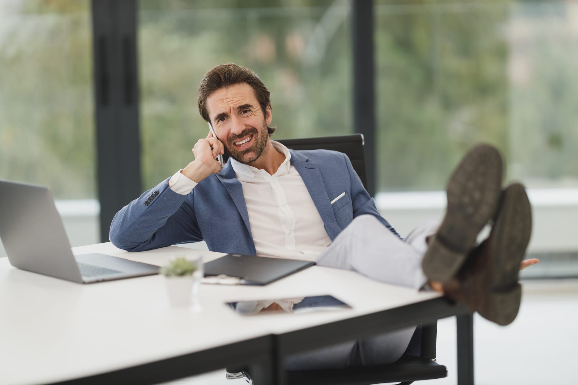 A businessman at his desk laughing on a phone call