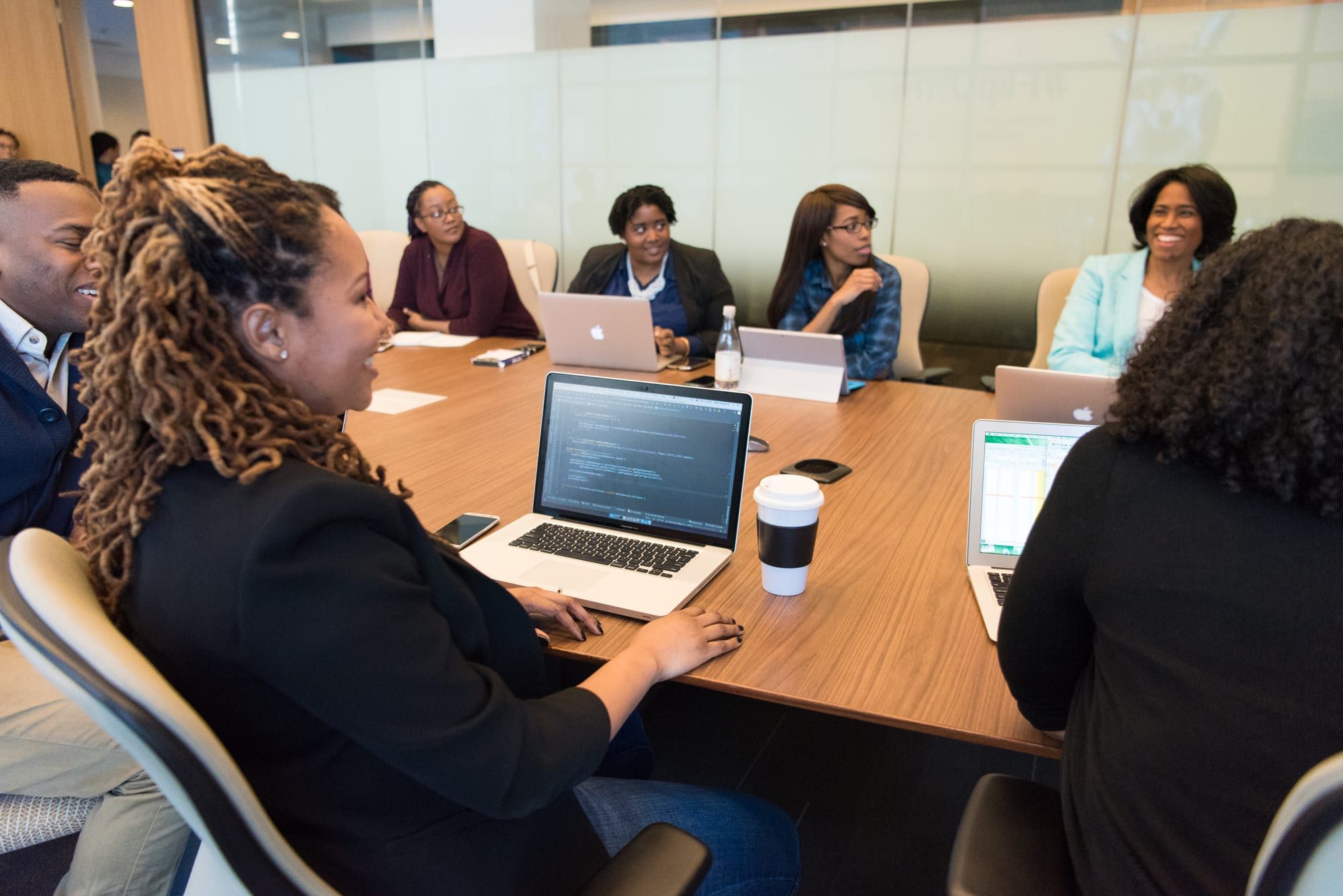 A team meeting around a conference table with laptops